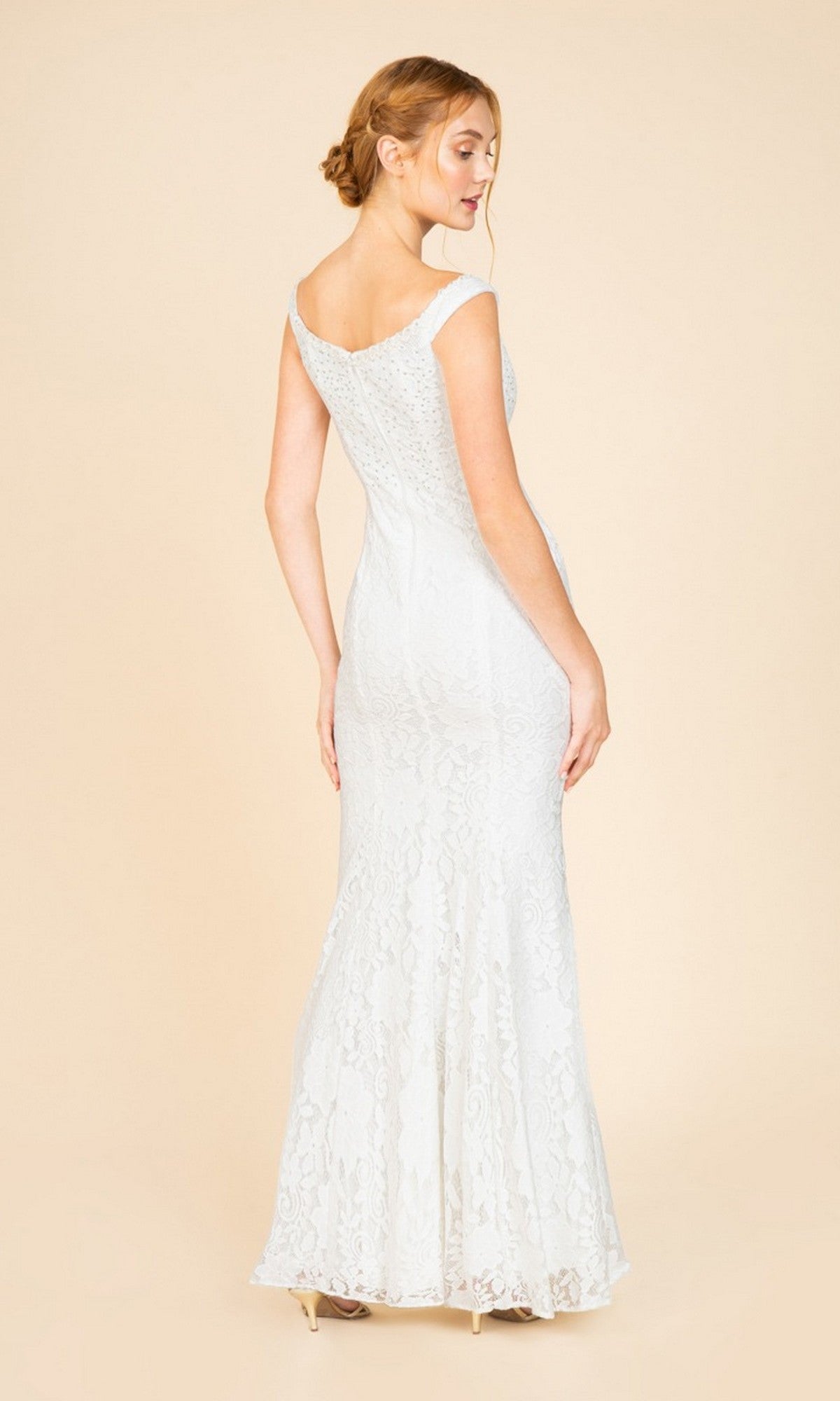 A woman poses against a plain beige background, wearing the Long Prom Dress: Eureka 8050—a fitted, off-the-shoulder lace gown with a subtly flared hem.